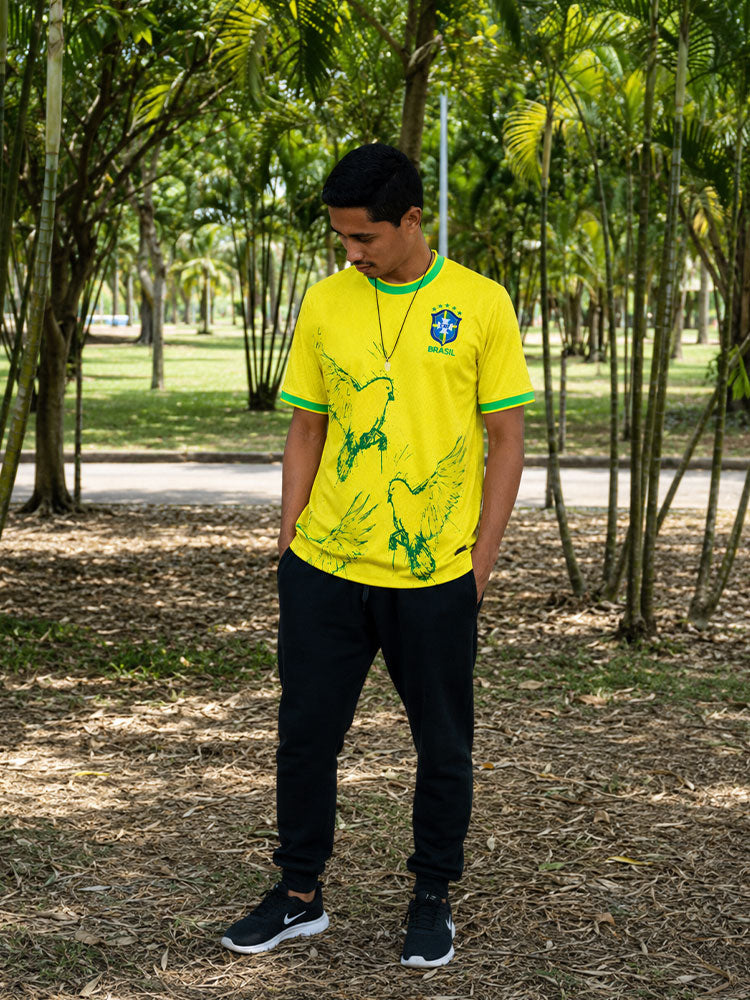 Homme portant le maillot Brésil jaune à oiseaux et colombes vertes, photo en extérieur sous les bambous